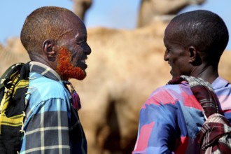 Merchants are having a lively conversation at the camel market in Babile, Camels in the background,