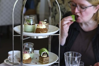 A woman enjoying high tea in Mona Vale with a selection of desserts and tea, Christchurch, Mona