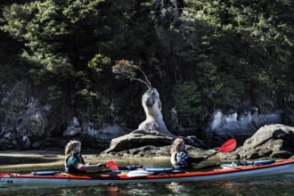 Two people kayaking in front of a rock formation on the water, Appletree Bay, Abel Tasman National