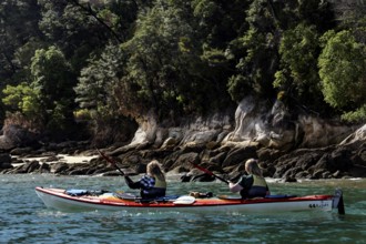 Two people paddle in a kayak along the coast of Adele Island, zero