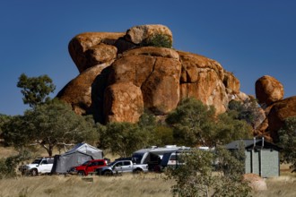 Campground surrounded by distinctive red rocks and vehicles under blue skies, Devil's Marbles,