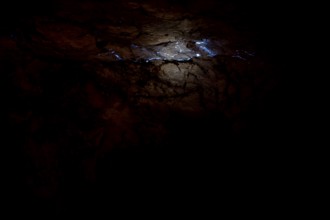 Shiny opalader in a dark layer of rock at Tom's Working Opal Mine, Coober Pedy, South Australia,