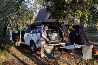 Forest campsite with a car tent and camping equipment in the evening light, Burdulba, Kakadu