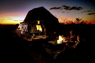 Camping in a van at sunset with bonfire in the Australian desert