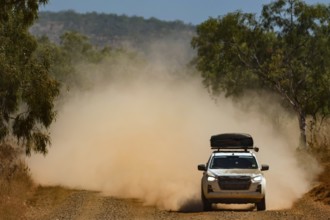 A four-wheel drive vehicle drives through clouds of dust on the unpaved Gibb River Road, Gibb River