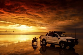 Sunset on Cable Beach with car, dog and sailboat in the distance, Broome, Western Australia,