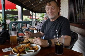 Man enjoying a meal and drinks on the terrace of Matso's Broome Brewery, Broome, Western Australia,