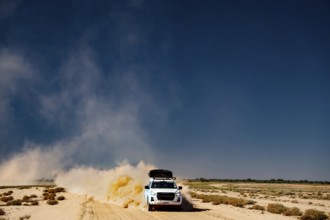 Four-wheel drive vehicle on dusty desert road