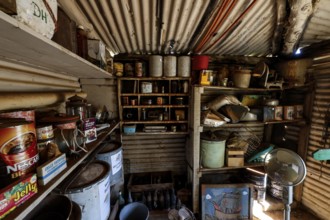 Pantry full of old tin cans and shelves under metal walls, zero