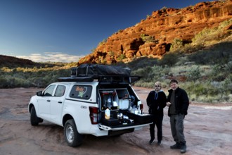 Off-road vehicle having breakfast break in front of impressive rocky backdrop in morning light,