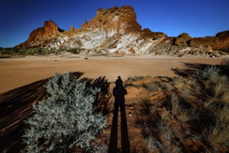 Shade stretches across the desert landscape of Rainbow Valley with distinctive rock formation, zero