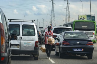 Hustle and bustle in Abidjan with cars stuck in traffic and a person crossing the road, Abidjan,