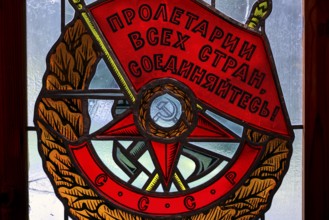 Socialist coat of arms with red banners and symbols in a stained glass window in Grutas Park,