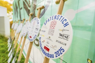 Several signs printed with logos announcing broadband expansion in 2025, fiberglass groundbreaking,