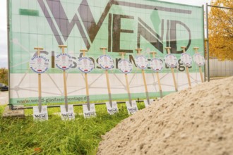 Signs announcing a broadband expansion are lined up in front of a construction fence, fibreglass