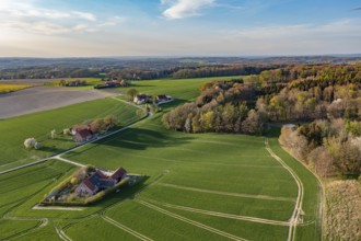Green fields and forests with small farms under blue spring sky, oblique aerial view, Osnabrücker