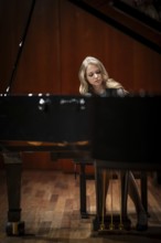 Young woman, pianist, with concentrated facial expression playing on a Steinway & Sons grand piano,