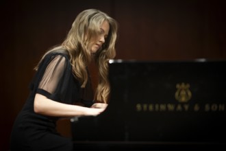 Young woman, pianist, pianist with concentrated facial expression playing on a Steinway & Sons