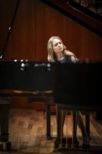 Young woman, pianist, with concentrated facial expression and closed eyes playing on a Steinway &
