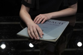 Hands of a young pianist rest on notes from Johann Sebastian Bach, Steinway & Sons-Flügel,