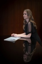 Young woman, pianist, in evening dress, with notes by Johann Sebastian Bach, supported on Steinway
