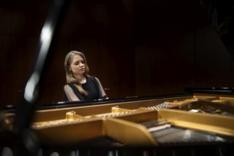 Young woman, pianist, in evening dress playing on an unfolded Steinway & Sons grand piano,