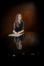 Young woman, pianist, with notes by Johann Sebastian Bach in concert hall, supported on Steinway &