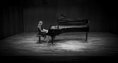 Young woman, pianist, in evening dress, in a concert hall, playing on a Steinway & Sons grand