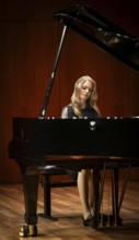 Young woman, pianist, with concentrated facial expression in a concert hall playing a Steinway &