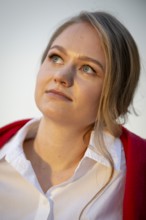 Portrait of a thought-looking young woman, pianist, wearing white blouse and red cardigan, in the