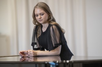 Young woman, pianist, in evening dress leaning on a Steinway & Sons grand piano, Stuttgart,