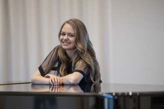 Smiling young woman, pianist, in evening dress leaning on a Steinway & Sons grand piano, Stuttgart,