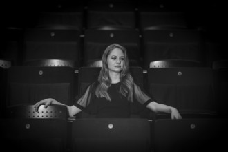 Young woman, pianist, in evening dress, sitting on chair in audience area, Stuttgart,