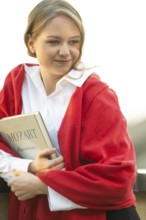 Self-confidently looking young woman, pianist, in white blouse and red cardigan, in the evening