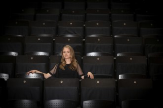 Young woman, pianist, in evening dress, sitting on chair in audience area, Stuttgart,