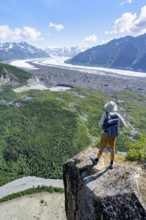 Young man on a rocky outcrop enjoying the view, view of impressive mountain scenery with Matanuska