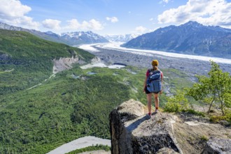 Young woman on a rocky outcrop enjoying the view, view of impressive mountain landscape with