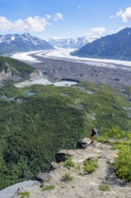 Young woman on a rocky outcrop enjoying the view, view of impressive mountain landscape with