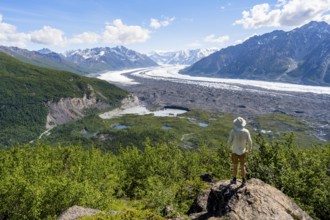 Young man enjoying the view of impressive mountain landscape with the Matanuska Glacier tongue,
