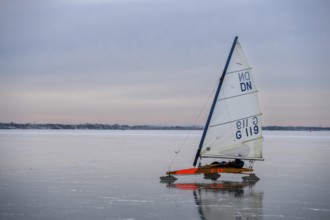 An ice sailboat glides across a frozen lake under a cloudy sky, Dümmer nature park Park, Lower