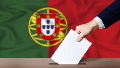 Portugal presidential vote 2026. Hand placing a ballot in ballot box with the Portuguese flag in