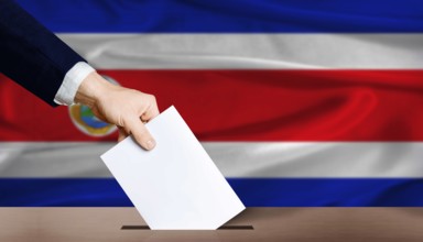 Costa Rica presidential vote 2026. Hand placing a ballot in ballot box with the Costa Rican flag in