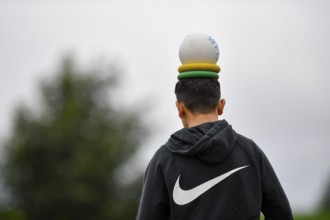 Person with a ball and rings on their head, outside in hoodie, sports and fun Olympics Sportfest