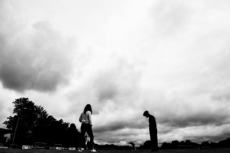 Two silhouettes of people under dramatically cloudy sky on a sports field, sports and fun Olympics