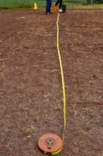A tape measure and a sports disc lie on an ash track, marking a point in competition, Lower Saxony,
