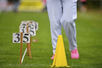 Person on grass with yellow hat and numbers, sporting activity, sports and fun Olympics Sportfest