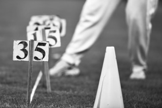 Black and white image of a person on grass with cones and numbers, Sports and Fun Olympics Sports