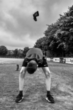 A boy throws a rubber boot on a sports field in a black and white shot, Sports and Fun Olympics
