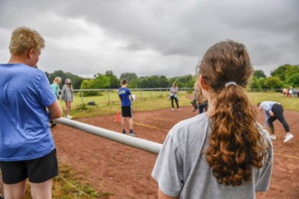 Young people watch a competition on a sports field under cloudy sky, Sport Sportfest Schule, Lower
