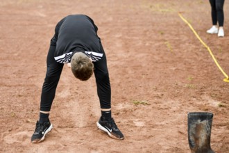 A teenager in sportswear throws a rubber boot on an ash track rubber boots long throw sports and